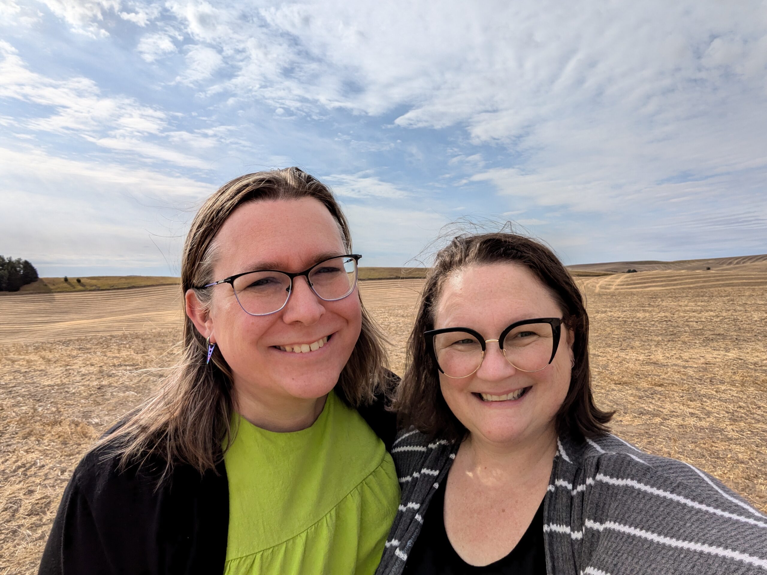 Two ladies smiling and standing in a farmed field